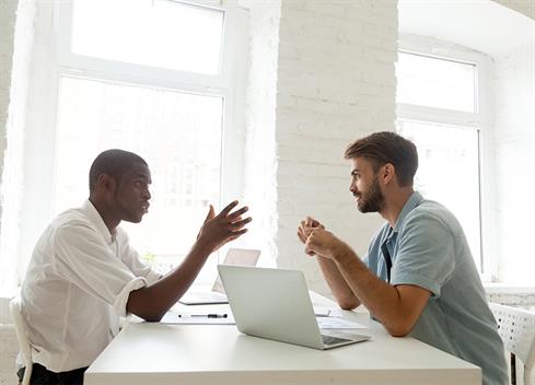 two men talking at desk