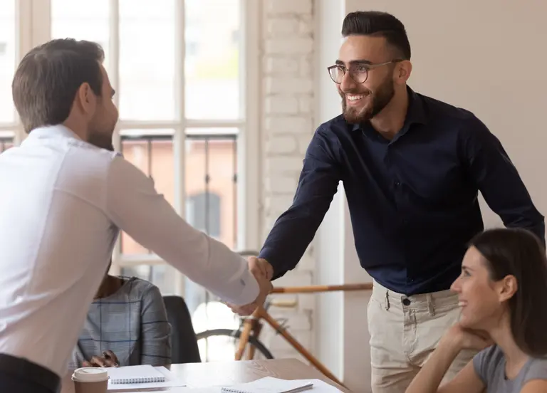 Male team leader shaking hands with young Arabic employee