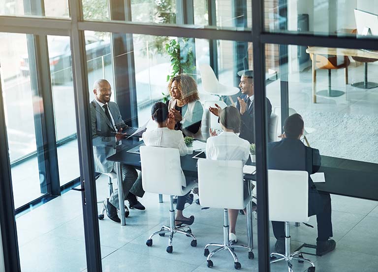 business people gathered around conference table clapping business people gathered around conference table clapping