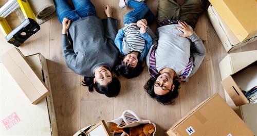 family lies on floor with moving boxes