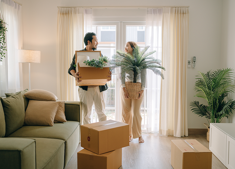 Two people smiling holding moving boxes in home